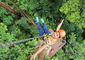 Woman enjoying a thrilling zipline experience in Phuket, Thailand's vibrant green forest.