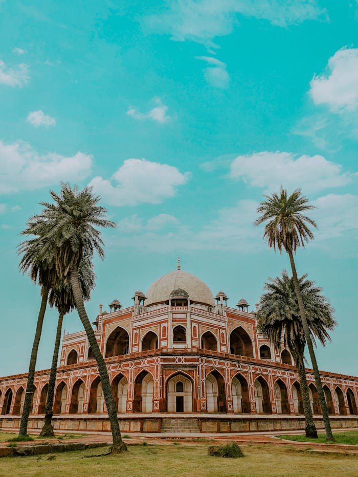 Delhi One Day Tour Explore Humayun's Tomb, a UNESCO World Heritage Site in Delhi, surrounded by palm trees and blue skies.