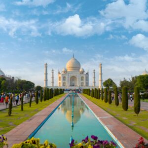 A beautiful view of the Taj Mahal in Agra, India, with clear blue skies and vibrant gardens.